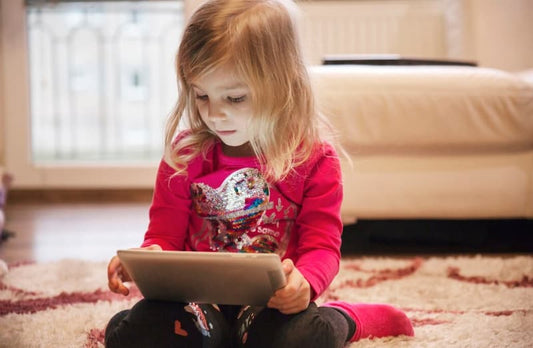 Enfant utilisant une tablette dans un environnement familial, illustrant l'impact des écrans sur le développement cognitif et social. -  Blog Pitchounart